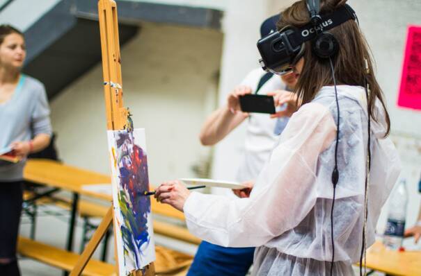 Une jeune fille fait de la peinture sur toile avec un casque de réalité virtuelle