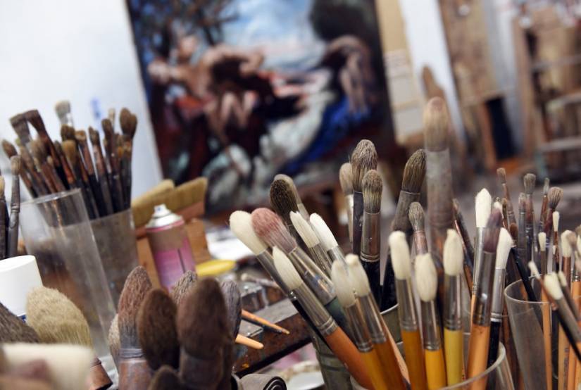 photo d'illustration montrant des pinceaux dans des pots dans un atelier avec une peinture en arrière plan