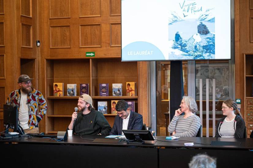 photo 1 : Autour d’une table, sont réunis l’animateur Victor Macé de Lépinay, le lauréat Jean Cremers, Hilaire Multon, le directeur régional des affaires culturelles des Hauts-de-France ainsi que deux femmes.  En arrière-plan, un diaporama affiche la bande-dessinée de Jean Cremers intitulée « vague de froid ».