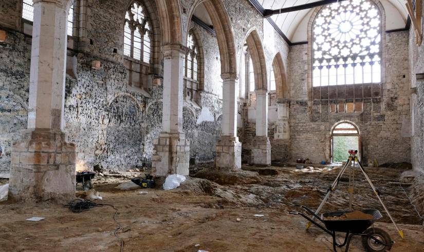 Le chantier en cours dans la nef de l'église. Au premier plan, une brouette et un téodolite. Au second plan, les niveaux archéologiques en cours de dégagement.