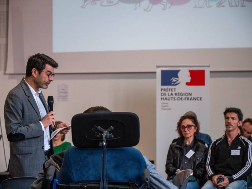 Photo 2 : le directeur régional des affaires culturelles des Hauts-de-France Hilaire Multon prend la parole devant le public. En arrière-plan, on peut voir un kakemono avec le logo du préfet de la région Hauts-de-France.