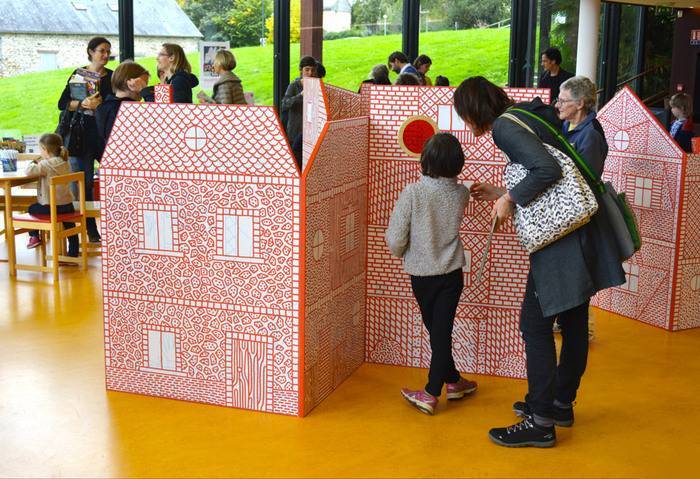 Public devant une maison en carton