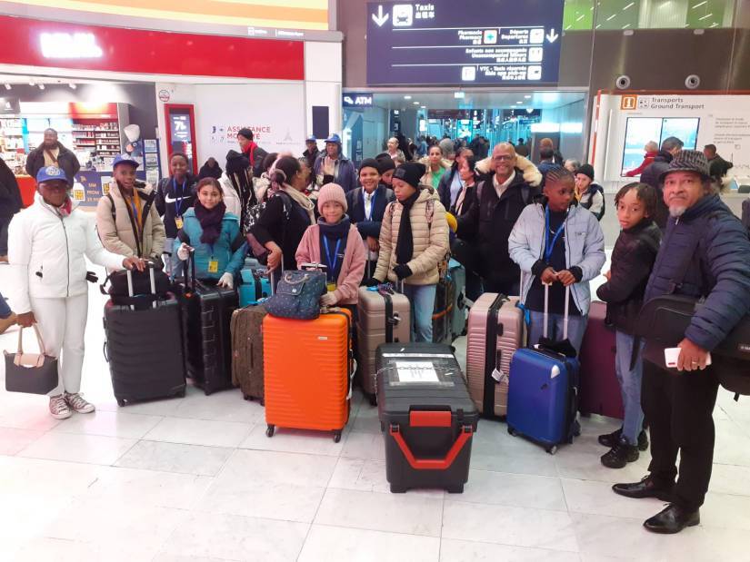 La délégation venue de Guadeloupe arrive en métropole et pose, souriants mais fatigués du voyage, avec leurs valises dans un hall de l'aéroport Charles de Gaulle.