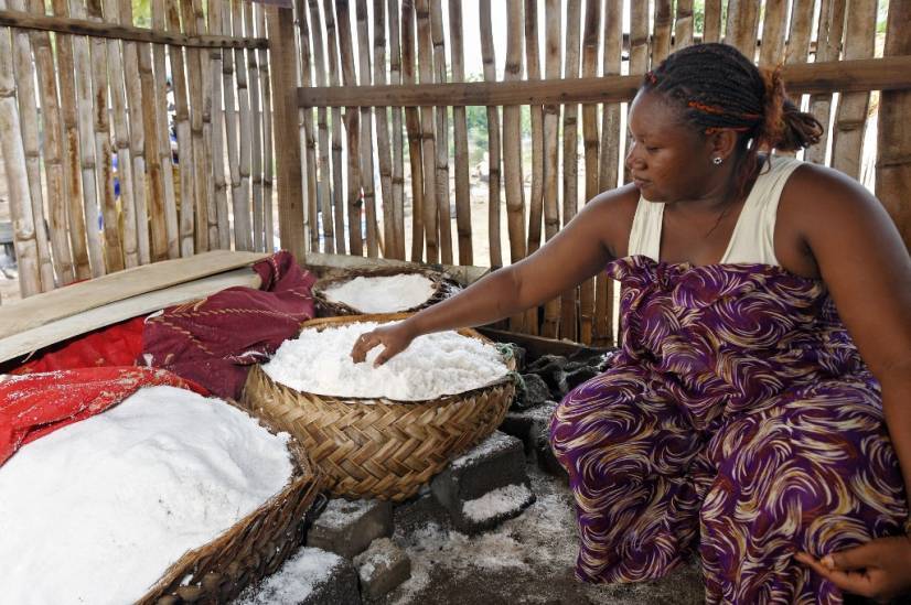 photo d'une femme a côté d'un panier contenant du sel. elle met sa main dedans