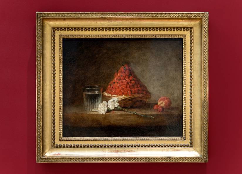 PHOTO 1 : Gros plan sur le tableau « Le panier de fraises » de Chardin, encadré sur un mur rouge qui fait ressortir le tableau et son cadre en or.