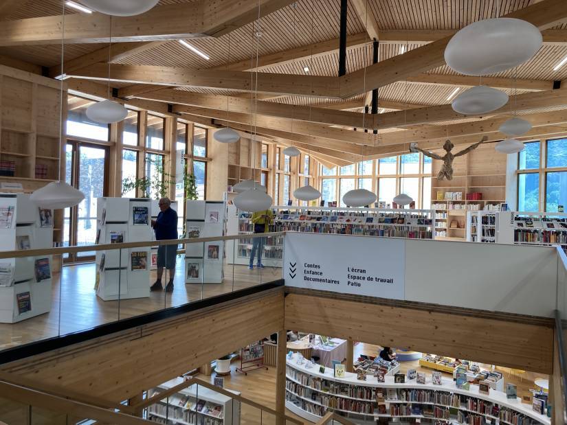 Vue de deux niveaux de la médiathèque avec des rangées de livre et du public