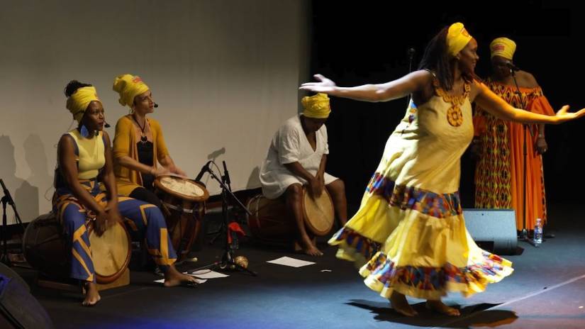 Danseuse guadeloupéenne tournant devant un groupe de musiciennes (percussions et chant).