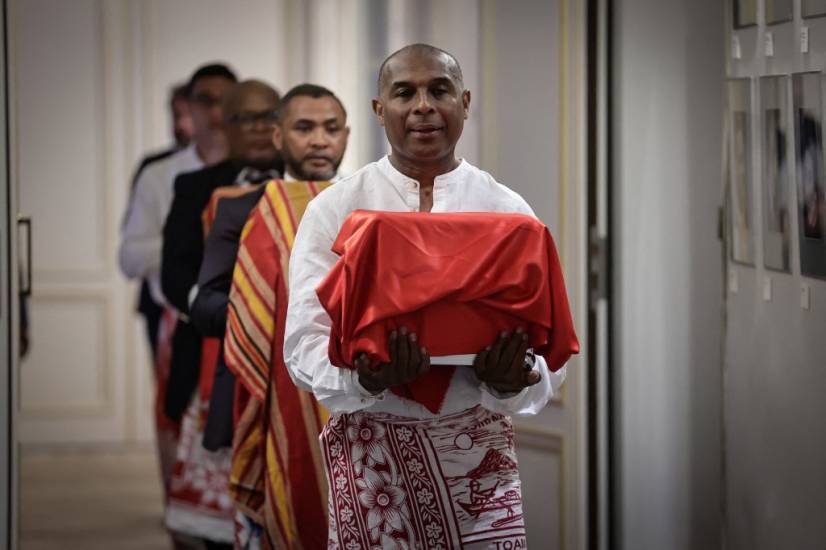 photo d'un homme portant un coffre recouvert d'un tissu rouge, suivi par quatre autres hommes