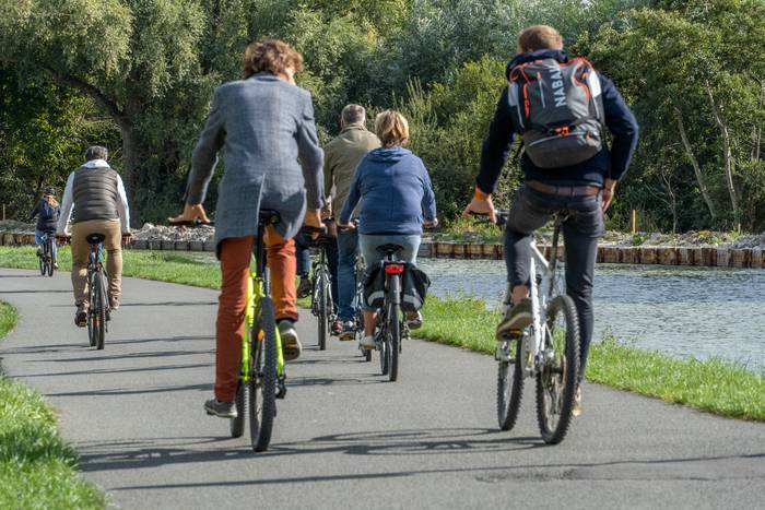De dos, des cyclistes roulent au bord de l'eau.