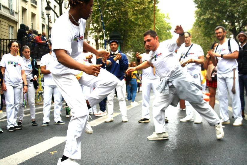 photo de deux personnes en train de faire de la capoeira dans la rue entourés de personnes