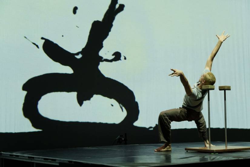 photo d'une personne en train de faire un mouvement de danse devant un &eacute;cran avec un signe qui imite le mouvement