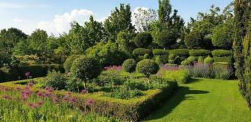PHOTO 2 : Ici, le jardin du mont des récollets. On y voit un jardin aménagé avec des allées de pelouse verte bien entretenue et des parterres de fleurs structurés. À l'intérieur de ces parterres, des buissons taillés en boules et des fleurs colorées, principalement violettes et roses, ajoutent une touche de couleur.
