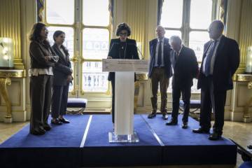 ministre faisant discours au pupitre, entourée de 5 personnes