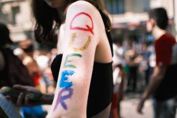 bras d'une femme avec inscription queer en lettres colorées