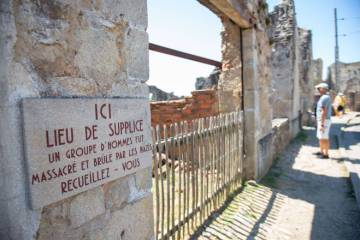 panneau appelant au recueillement dans village oradour sur glane avec visiteur en arrière plan