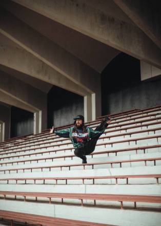photo d'un danseur de break dance dans des gradins d'un stade en &eacute;quilibre sur un banc