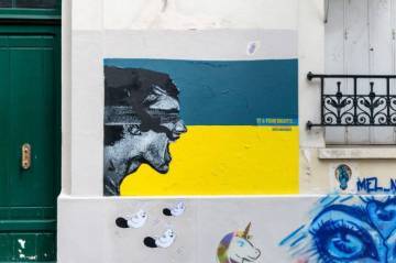 photo d'un graffiti sur le mur d'un immeuble parisien représentant le drapeau ukrainien jaune et bleu et le visage d'une personne de profil en train de crier