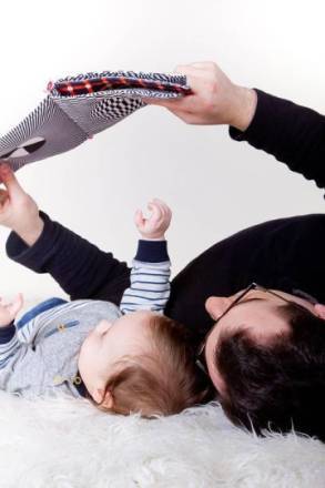 un p&egrave;re et son b&eacute;b&eacute; lisant allong&eacute;s