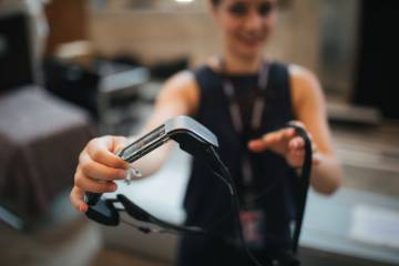 photo avec au premier plan des lunettes connectées, présentées par une jeune femme au second plan, floue