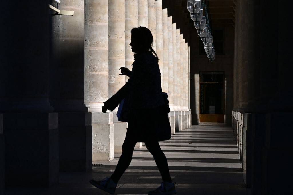 personne qui marche sous les arcades du palais royal contre jour