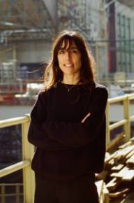 photo de devrim bayar, grande femme brune. Elle se tient debout les bras croisés dans un décor de chantier