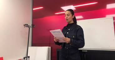 photo d'une jeune femme debout avec un papier à la main en train de parler