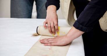 photo d'une personne en train de dérouler une bandelette de torah - ou mappot - sur une table