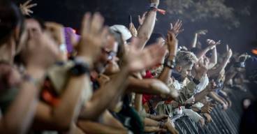 photo prise de nuit dans la foule d'un festival avec des personnes qui regardent un concert et lèvent les mains