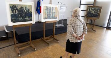 photo des trois tableaux de fédor Loewenstein posés sur des chevalets avec une personne âgée en train de les regarder