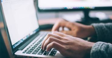 Zoom sur des mains en train de taper sur un clavier d'ordinateur portable