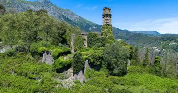 photo d'un couvent dans un paysage de montagne. le couvent est en ruine, recouvert par des arbres et de la végétation