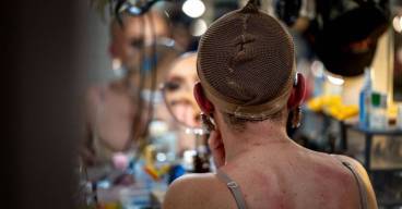 photo d'une personne en train de se maquiller devant un miroir avec un filet sur la tête pour mettre une perruque
