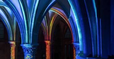 Les colonnes de l'Abbaye du Mont Saint-Michel sont éclairées par des lumières aux reflets bleu-orangé.