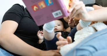 Un bébé et une famille lisent ensemble, promouvant l'amour et l'éducation. Cadre intérieur confortable.