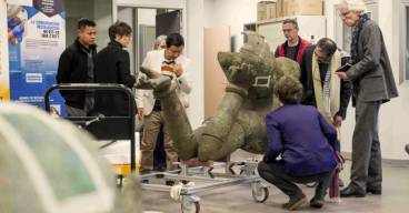 Examen par un groupe de personnes de la statue colossale en bronze du Vishnou couché du Mébon occidental, au laboratoire Arc'Antique