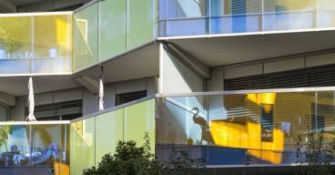 photo en gros plan de balcons d'un immeuble récent avec le reflet du soleil