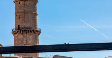 photo d'une tour extérieure sous un ciel bleu et d'une passerelle avec des personnes dessus