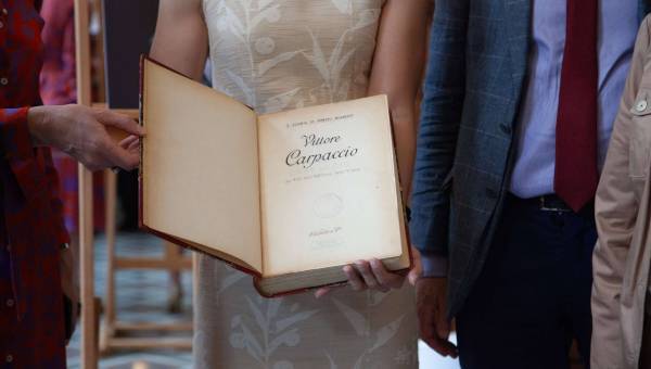 photo de quatre personnes dont une tenant un livre dans les mains ouvert à la première page
