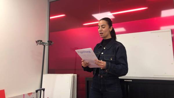 photo d'une jeune femme debout avec un papier à la main en train de parler