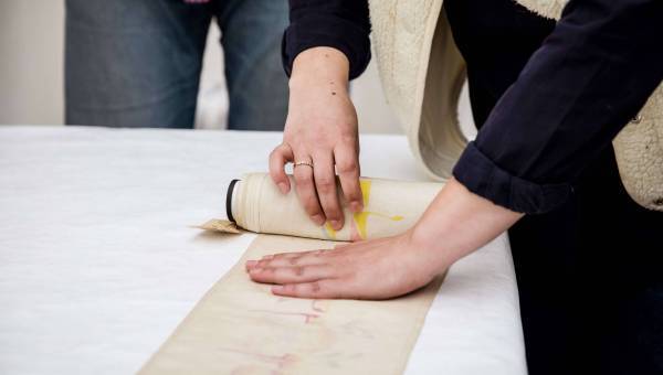 photo d'une personne en train de dérouler une bandelette de torah - ou mappot - sur une table