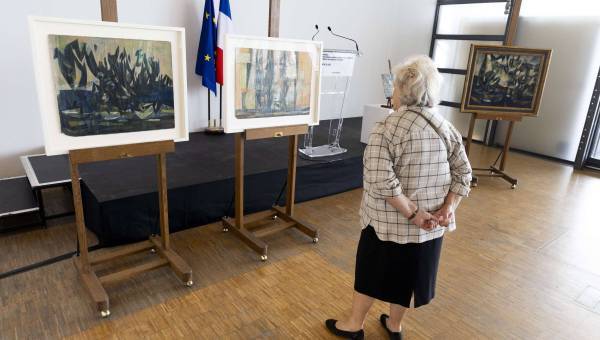 photo des trois tableaux de fédor Loewenstein posés sur des chevalets avec une personne âgée en train de les regarder