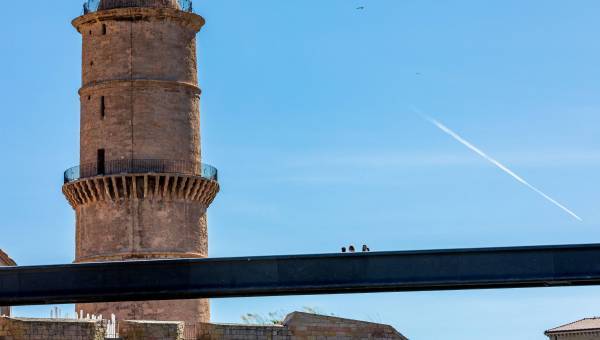 photo d'une tour extérieure sous un ciel bleu et d'une passerelle avec des personnes dessus