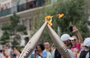 deux flammes olympiques se rencontrent avec du public en arrière plan