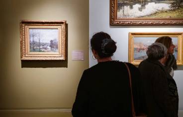 Dans une salle du musée Antoine Lecuyer à Soisssons, une visiteuse de dos découvre la peinture de Pissarro précédée de la mention "100 œuvres qui racontent le climat"