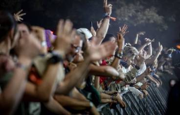 photo prise de nuit dans la foule d'un festival avec des personnes qui regardent un concert et lèvent les mains