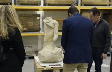 Trois personnes regardent une statue en pierre provenant du site de Roquepertuse, dans l'atelier pierre du CICRP.