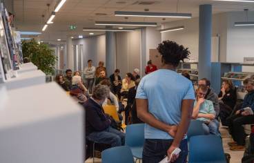 Sur la photographie de couverture, on voit Kamini de dos, et des personnes assises face à lui.