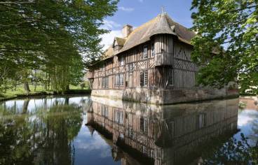 Photo du manoir de Coupesarte en Normandie, maison à colombage au bord d'un plan d'eau avec des arbres