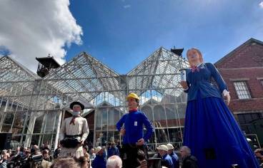 Sur la photographie de couverture, trois grands géants des Flandres sont exposés pour l’évènement. Le premier géant, à gauche, représente un vieil homme habillé en costume traditionnel avec un chapeau.  Le géant central est un personnage vêtu d'un casque de chantier jaune et d'une chemise bleue, rappelant un ouvrier. À droite, le troisième représente une femme en robe bleue. Ces géants se tiennent devant une grande structure vitrée. On peut voir un groupe de personnes rassemblées autour des statues, semblant participer à l'événement.
