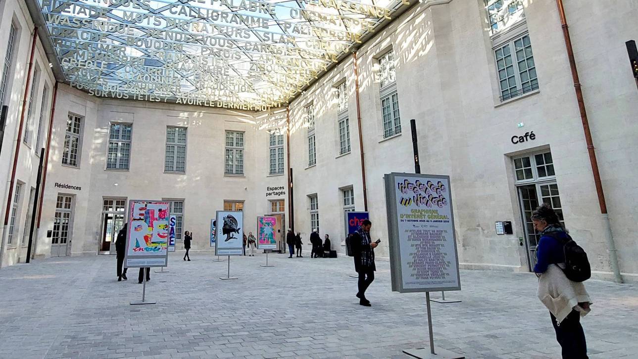 photo de la Cité internationale de la langue française à Villers-Cotterêts sous une verrière avec seize affiches exposées et des visiteurs qui les regardent